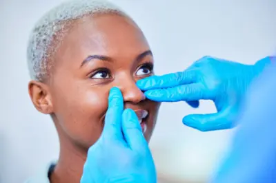 Nasenkorrektur in der Türkei: Arzt untersucht die Nasenflügel einer Patientin vor einer Nasenflügelverkleinerung (Alarplastik)
