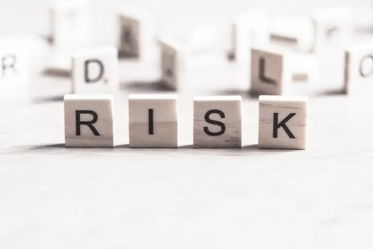 Holzbuchstaben, die das Wort „RISK“ (Risiko) bilden und die Risiken sowie möglichen Komplikationen einer Stirnverkleinerungsoperation symbolisieren.