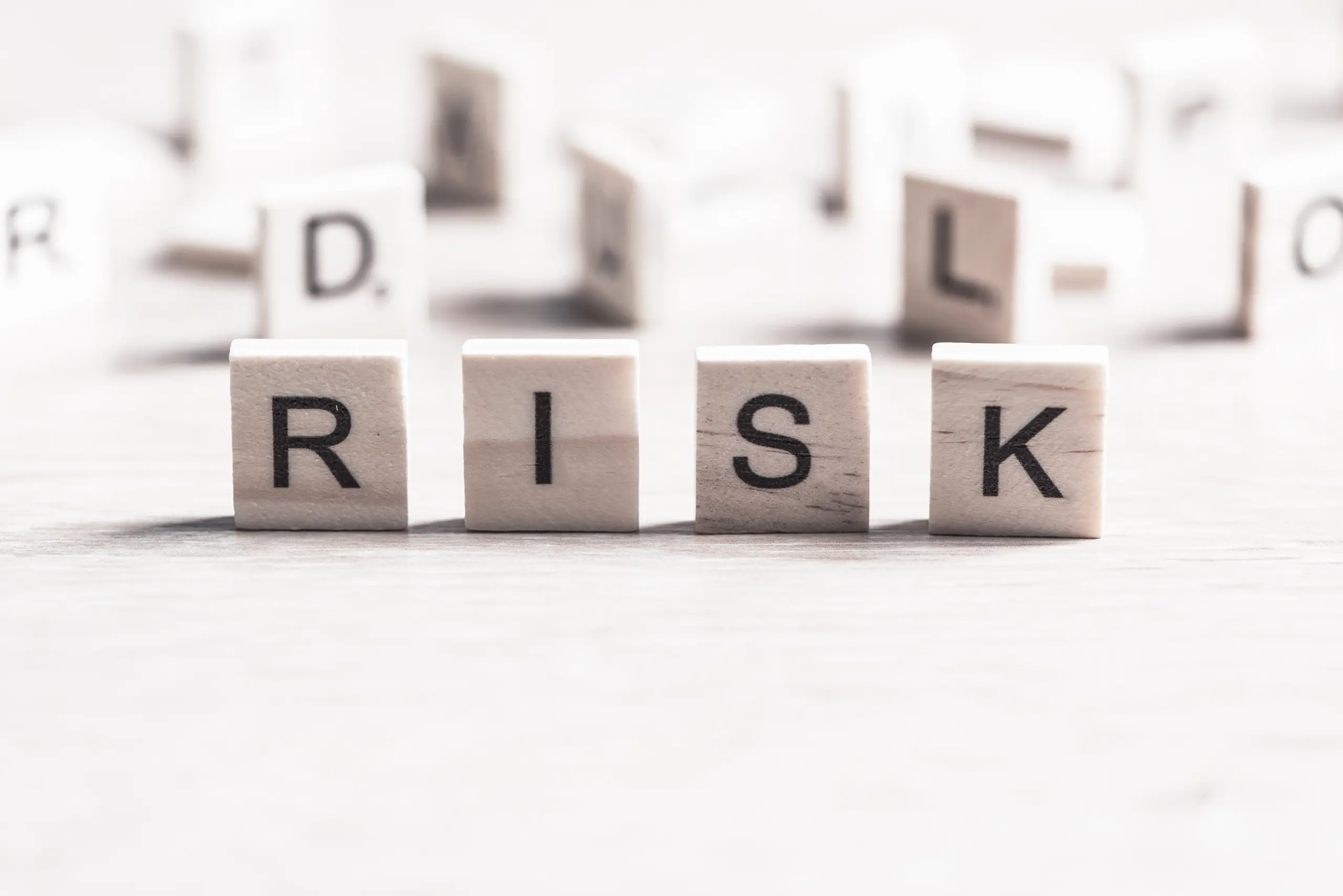 Wooden letter tiles spelling the word RISK, symbolizing the risks and complications of forehead reduction surgery
